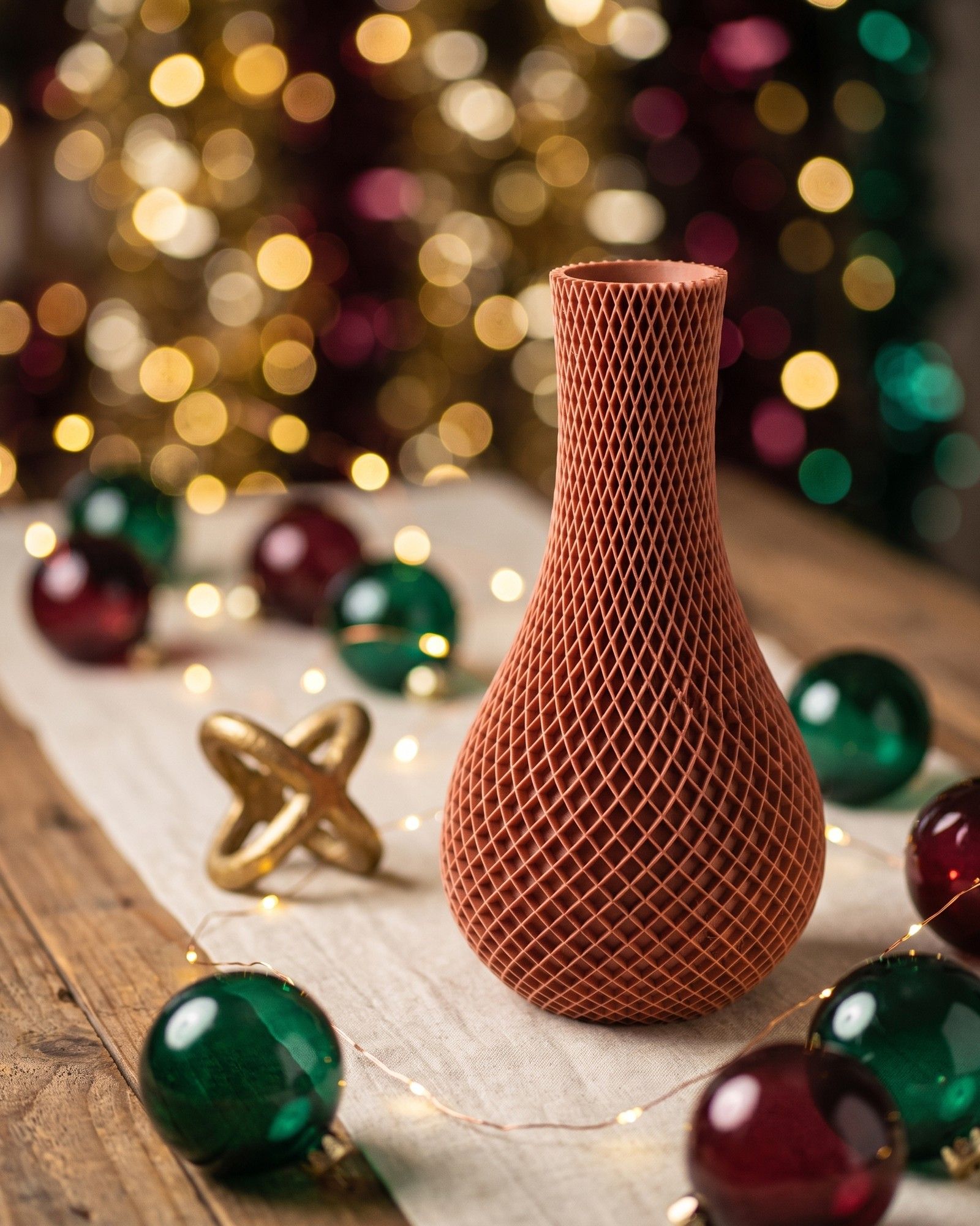 Dieselbe Vase auf einem Holztisch mit Christbaumkugeln, Lichterkette und warmem Bokeh im Hintergrund; Form, Rautenmuster und Farbe unverändert